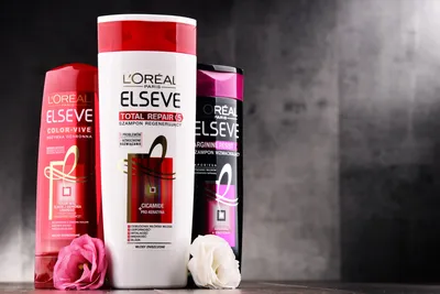 Уличная вывеска с логотипом L`Oreal. Размытый фон офисного центра и идущих людей картинки